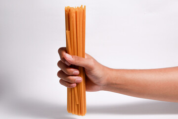 Male hand holding fettuccine spaghetti on isolated white background