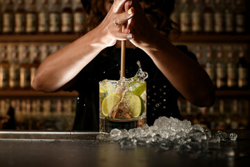 Female bartender vigorously squeezes lemons in a glass with a drink using the Turbo Swizzle Barta...
