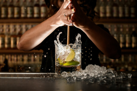Female bartender energetically inserts a Turbo Swizzle Barta muddler into a glass with a cocktail