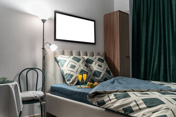 breakfast in bed. On bed is tray with orange juice in glasses, fruits and croissants. bed linen is green, dark sheet, pillowcase on pillow, dark green curtains on window. design of modern bedroom.