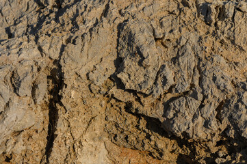 Textures of weathered rock formation illuminated by warm sunlight at the edge of a rugged landscape.