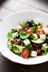 Healthy Salad with Feta Cheese, Black Olives, Cucumber and Cherry Tomatoes. Wooden background. Close up.