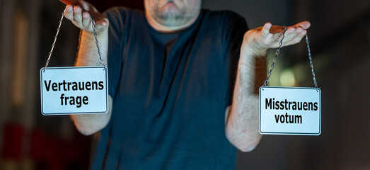 Mann hält zwei Schilder hoch mit der Aufschrift 'Misstrauensvotum' und ' Vertrauensfrage. Symbol...