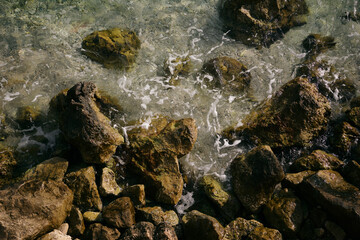 the sea waves are beating against the rocks covered with a green coating
