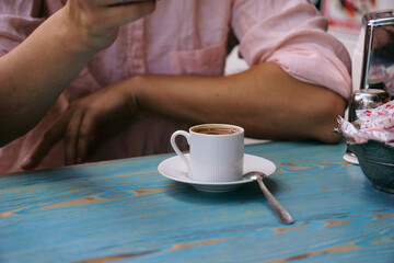 a man is sitting at a table and drinking coffee from a cup. Breakfast at the coffee shop
