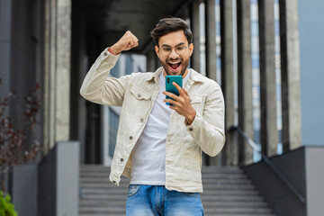 Amazed Indian man use mobile smartphone celebrating win good message news, lottery jackpot victory...