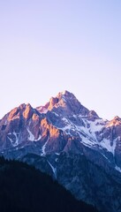 Fototapeta premium Majestic Sunrise Over Snow-Capped Mountain Peak in the Serene Wilderness of the Alps