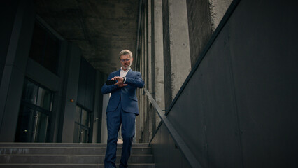 Caucasian mature old man businessman senior business employer walking outdoors on stairs near...