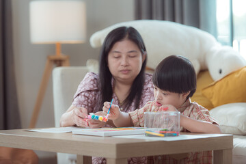 A special child with his mom paint and coloring together in the living room of the house