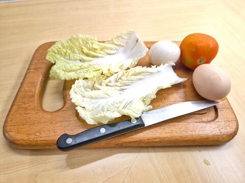 A knife is on a cutting board with lettuce tomato and an egg. Selective focus. - Powered by Adobe