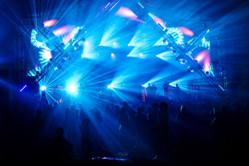 Outdoor concert with a brightly lit stage and shadows during the concert, crowd at a concert in a...