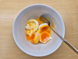 A bowl of eggs with a yellow yolk and a white egg white. The eggs are broken and mixed together. Selective focus.