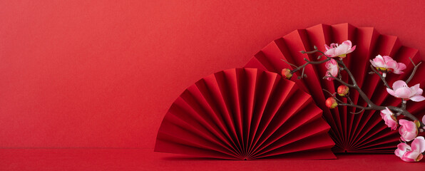 Red paper fans and cherry blossoms on a vibrant background symbolize Chinese new year 2025...