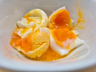 A bowl of eggs with a yellow yolk and a white egg white. The eggs are broken and mixed together. Selective focus.