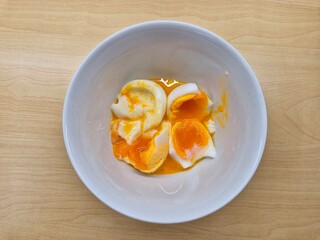 A bowl of eggs with a yellow yolk and a white egg white. The eggs are broken and mixed together. Selective focus.