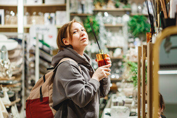 Middle aged woman looking at different casual clothes while shopping in mall
