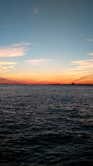 Obraz premium A serene ocean view during sunset with vibrant colors and a calm horizon.