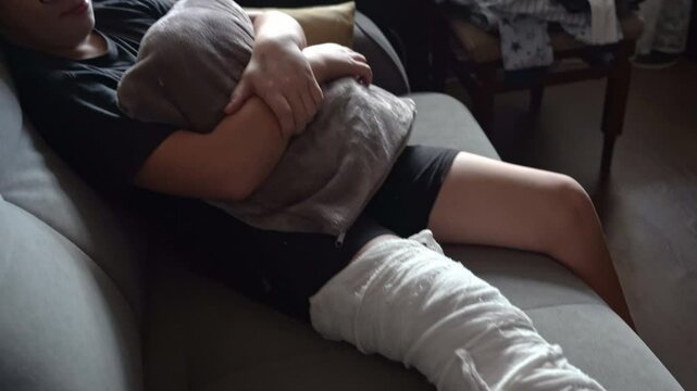 Boy recovering on sofa with leg in plaster cast