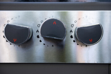 A closeup view of sleek stainless steel stove knobs featured prominently in a modern kitchen