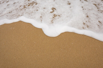 Background close-up of ocean waves rolling on the sand on the beach, with a sand texture. Sandy beach by the sea. A deserted area. Realistic seamless illustration with fine details.