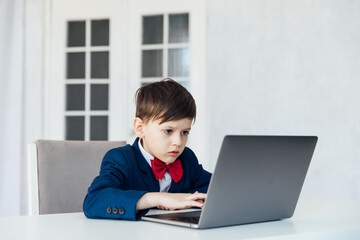 Schoolboy In Jacket At Desk Playing In Laptop Online