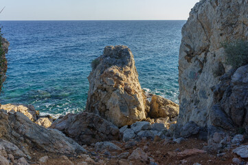 Serene coastal view with rocky formations and calm blue waters at sunset by the shore.