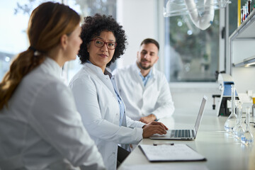 Obraz premium Team of biotechnologists cooperating while reading scientific data on a computer in laboratory.