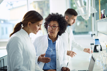 Female scientists talking while working together in laboratory. 