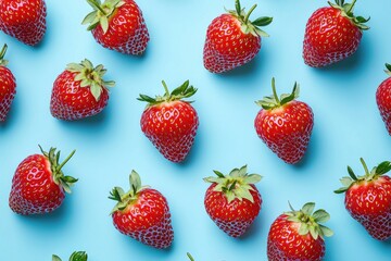 A flat lay of fresh strawberries on a light blue background.