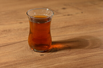 Captivating amber tea in a delicate glass on a wooden table illuminated by warm light