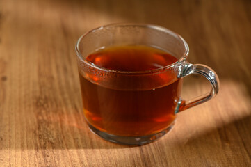 Cozy afternoon tea in a clear glass mug on a rustic wooden table inviting warmth and relaxation