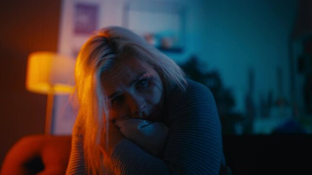 Anxious middle-aged female sitting on sofa alone, rocking back and forth