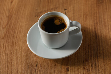 A quiet moment with a steaming cup of coffee resting on a wooden table in the soft morning light