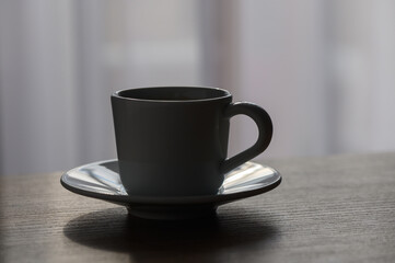 A delicate cup and saucer bathed in gentle morning light on a wooden table