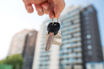 woman real estate agent holding house key on background of new buildings. Purchase concept, outdoor
