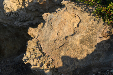 A close-up view of a weathered rock formation illuminated by golden sunset light in a natural...