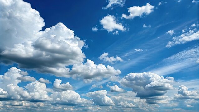 A brilliant blue sky is dotted with big white clouds that resemble cotton candy tufts floating effortlessly across the horizon, blues, sky formations, clouds, natural scenery, cotton candy