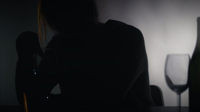 Silhouette of a woman coping with depression by drinking, difficult period