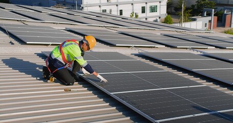 engineer Technician in safety gear installs solar panels on a roof under a clear sky, showcasing renewable energy solutions