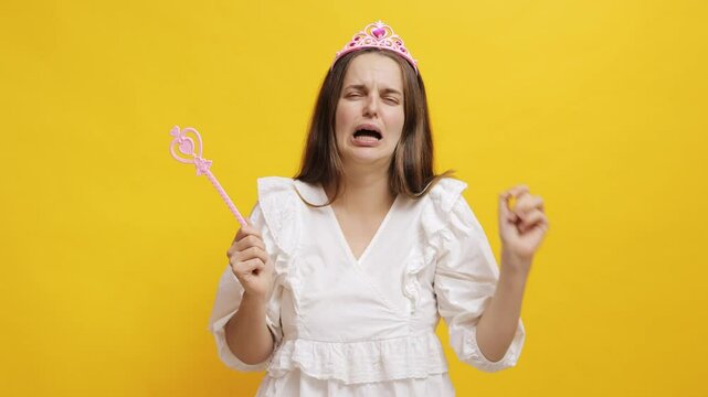 A princess with a wand shows emotion against a bright yellow background