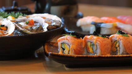 Variety of colorful sushi rolls and sashimi on wooden table, fresh seafood ingredients. Japanese Cuisine and Culinary Art