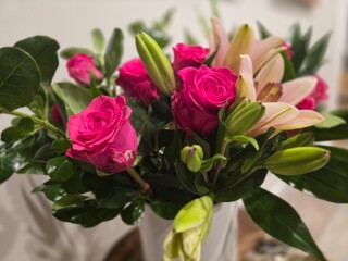 This captivating image showcases a stunning bouquet of pink roses and lilies arranged in a white ceramic vase. The vibrant colors and delicate blooms create a sense of elegance and beauty.