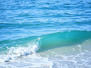 Wave gently lapping at the shore in a serene blue ocean scene, beach scenery, natural beauty, blue hue