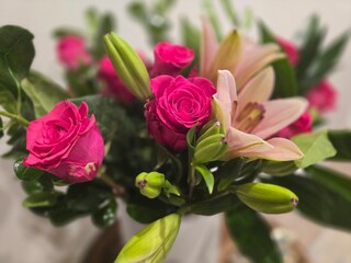 This captivating image showcases a stunning bouquet of pink roses and lilies arranged in a white ceramic vase. The vibrant colors and delicate blooms create a sense of elegance and beauty.
