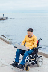 man sitting in wheelchair working on laptop online