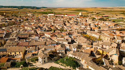 Obraz premium Panoramic view of the historic town of Astudillo, Spain, showcasing the medieval La Mota Castle and traditional hillside wineries. Captures rural charm and architectural heritage.