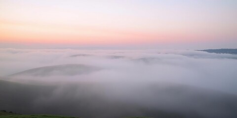 Obraz premium Early morning fog rolling over the hills with soft pink hues of sunrise, soft focus, misty atmosphere, landscape