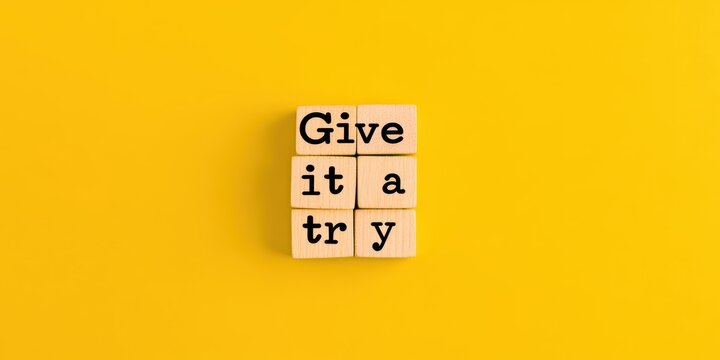 “Give it a try” message on wooden blocks with yellow background, motivational theme.