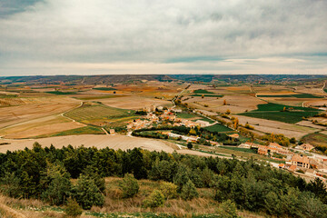 Panoramic view of Castrojeriz, Spain, as seen from the castle, surrounded by vast farmland. Captures the charm of rural Spanish landscapes and historic architecture.