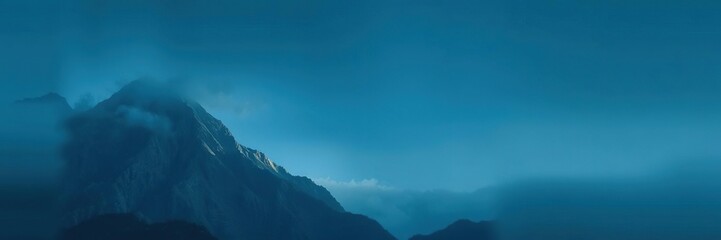 Fototapeta premium A majestic mountain peak with a dark blue gradient of mist and cloud, outdoorphotography, misty, bluedeviation